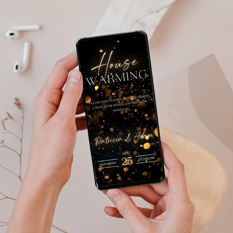 K&ouml;nnte beinhalten: Ein schwarzes Smartphone mit einer goldenen Einladung zu einer Einweihungsfeier auf dem Bildschirm. Die Einladung hat einen goldenen Glitzer-Hintergrund mit dem Text "House Warming" und den Namen "Patricia & Adam". Datum und Uhrzeit der Party sind mit "Samstag, 25. August um 14:00 Uhr" angegeben.