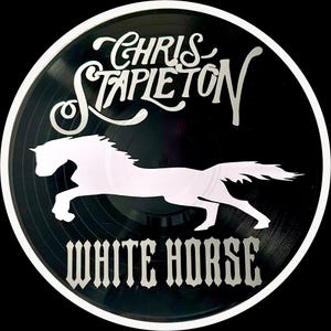 May include: A black vinyl record with a white silhouette of a horse running. The text "Chris Stapleton White Horse" is printed in white on the record.