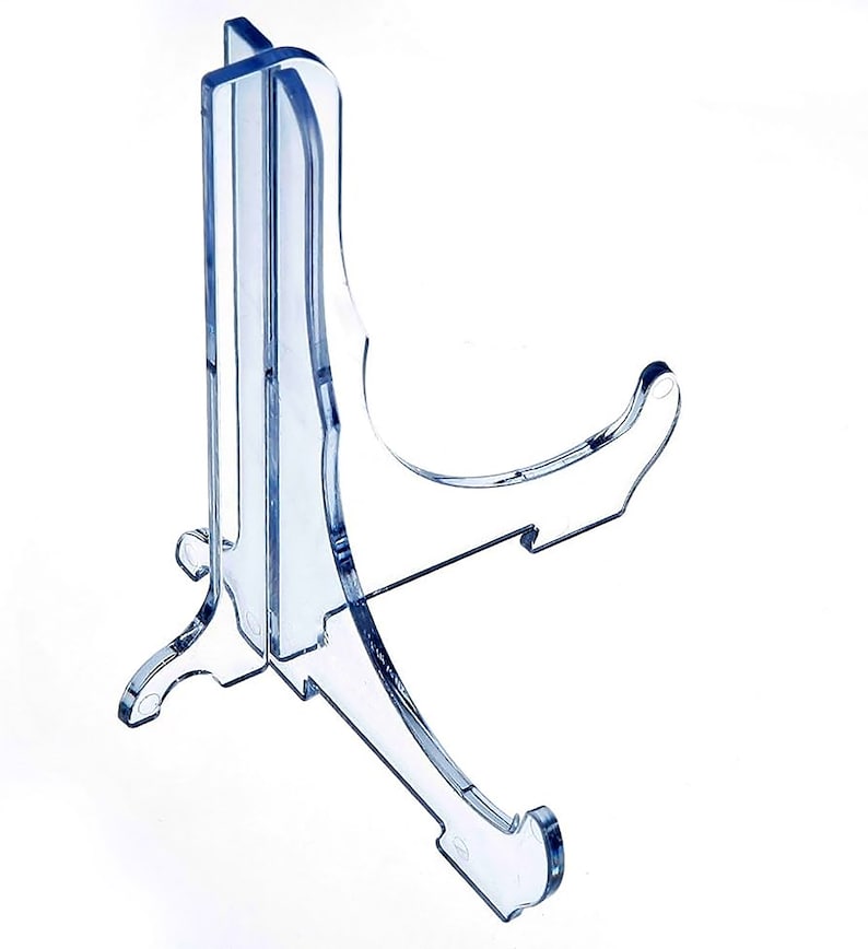 Puede incluir: Un soporte de exhibici&oacute;n de pl&aacute;stico transparente con una base curva y una parte posterior recta. El soporte est&aacute; dise&ntilde;ado para sostener un plato u otro objeto plano.