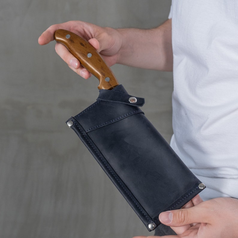 May include: A black leather sheath with a snap closure, holding a wooden handled knife.