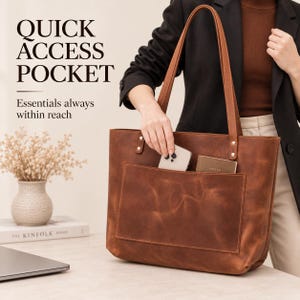 Puede incluir: Un bolso tote de cuero marr&oacute;n con un bolsillo exterior grande de acceso r&aacute;pido. El texto QUICK ACCESS POCKET y Essentials always within reach est&aacute; impreso a la izquierda. El bolso tiene dos correas largas sujetas con remaches met&aacute;licos.