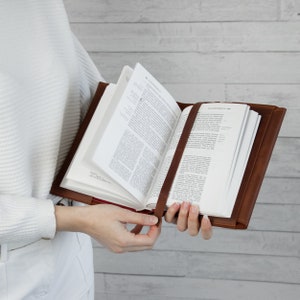 May include: A brown leather Bible cover with a bookmark. The Bible is open to a page with text.