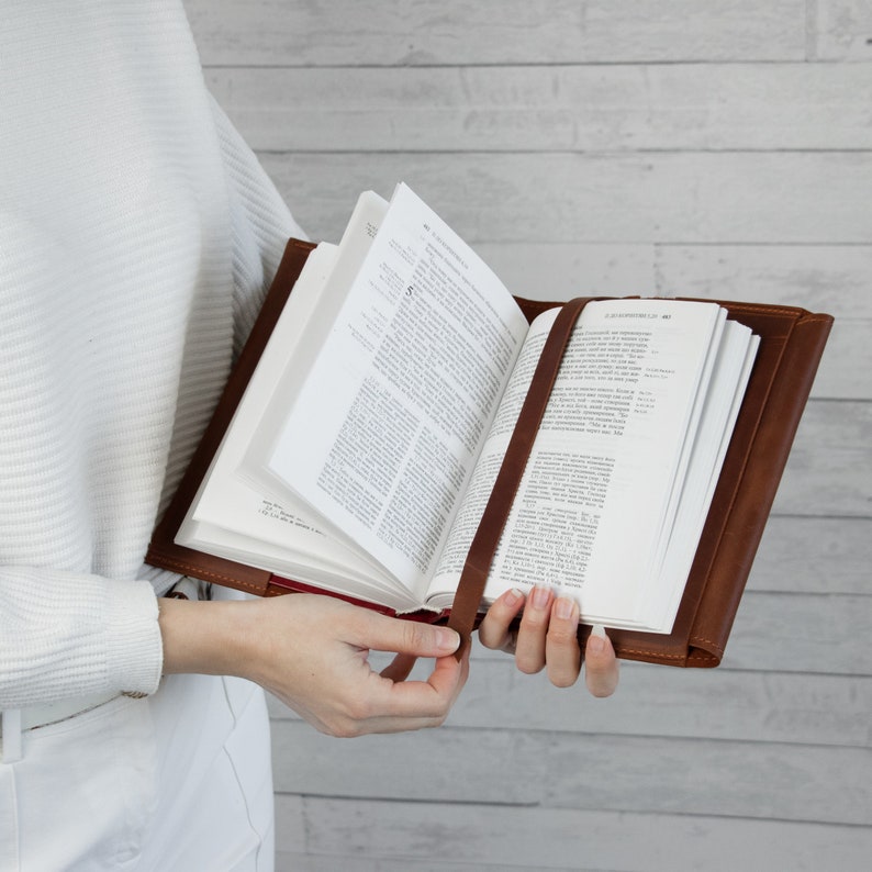 May include: A brown leather Bible cover with a bookmark. The Bible is open to a page with text.