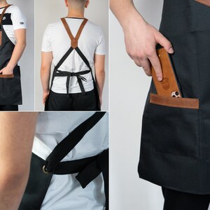 May include: Black canvas apron with brown leather accents and a large pocket on the front. The apron has adjustable straps and a phone pocket.
