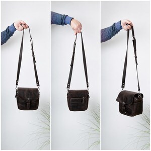 May include: A dark brown leather crossbody bag featuring a fold-over flap with a metal buckle closure, an adjustable shoulder strap, and a zippered pocket on the exterior. The bag is shown from the front, back, and side angles to display its design.