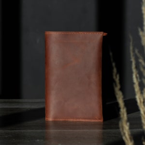 May include: A brown leather wallet with a stitched edge.