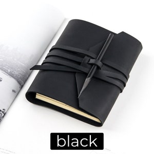 May include: A black leather journal with a wrap-around closure and a pencil. The journal is closed with a series of black leather straps. The word "black" is displayed in a black rectangle at the bottom of the image.