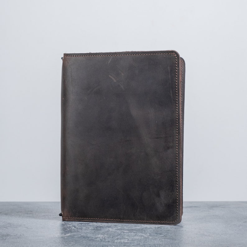May include: A dark brown leather notebook with a zipper closure.