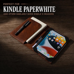 K&ouml;nnte beinhalten: Eine braune Lederh&uuml;lle mit einem Notizblock und einem schwarzen Stift auf der linken Seite sowie einem Tablet, das mit schwarzen Eckb&auml;ndern auf der rechten Seite befestigt ist. Der Text lautet: PERFECT FOR KINDLE PAPERWHITE AND OTHER SIMILARLY SIZED KINDLE E-READERS.
