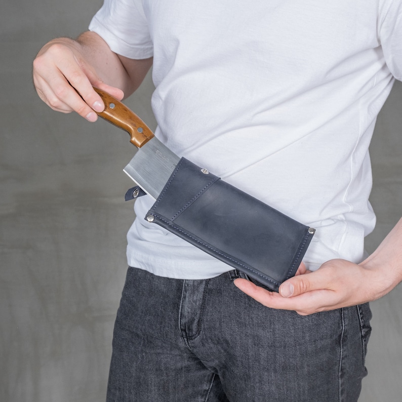 May include: A blue leather sheath with a brown wooden handle knife inside. The sheath is secured to a person's belt.