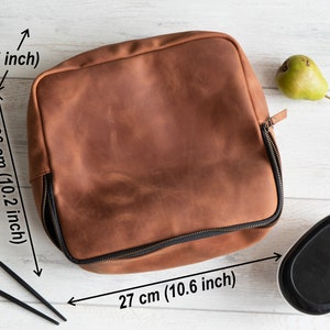May include: A brown leather lunch bag with a zipper closure. The bag measures 10.2 inches tall, 10.6 inches wide, and 4.7 inches deep.