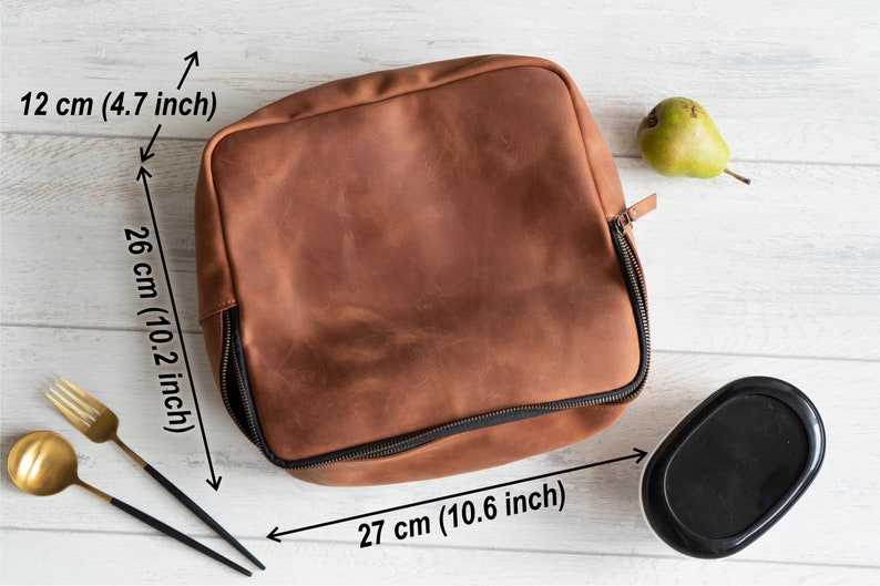 May include: A brown leather lunch bag with a zipper closure. The bag measures 10.2 inches tall, 10.6 inches wide, and 4.7 inches deep.