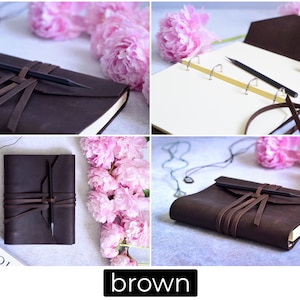 May include: A brown leather journal with a pencil secured by a leather strap. The journal is open in one image, revealing blank pages and gold-colored rings. Pink peonies and jewelry are in the background. The word "brown" is in a black rectangle.
