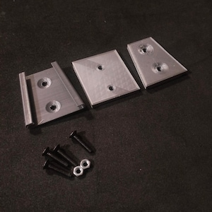 May include: Three gray plastic brackets with three black screws and two silver nuts. The brackets have holes for mounting.