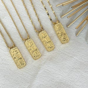 Könnte beinhalten: Goldfarbene Halsketten mit rechteckigen Anhängern. Jeder Anhänger zeigt eine andere Zahl: 333, 111, 444 und 888. Die Halsketten haben zarte Ketten und eine strukturierte Oberfläche auf den Anhängern.