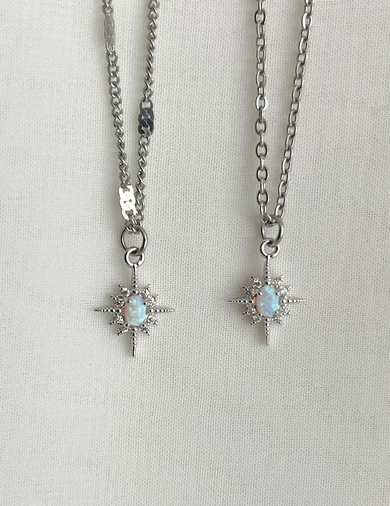 May include: Two silver necklaces with opal starburst pendants. The necklaces have different chain styles.