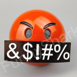 May include: A glossy orange sphere with a face showing anger, featuring black eyebrows and eye sockets. A black rectangle covers the mouth, displaying white symbols: & $ ! # %.
