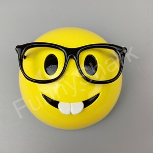 Puede incluir: Cara sonriente amarilla con gafas de montura negra y una amplia sonrisa.