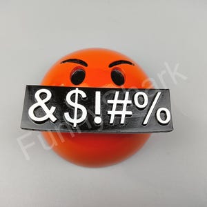 May include: An orange emoji with angry eyebrows and black eyes, a black rectangle covers the mouth with white symbols: & $ ! # %. The emoji is a sphere shape.