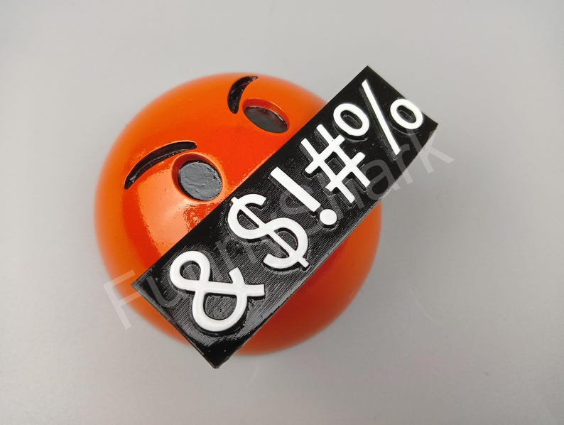 May include: An orange emoji with black eyes and a black rectangle covering its mouth. The rectangle has white text that includes an exclamation mark, a dollar sign, a hash, a percent sign, and an ampersand.