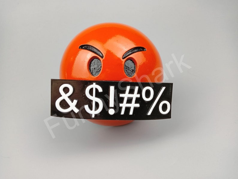 May include: A glossy orange sphere with a face showing anger, featuring black eyebrows and eye sockets. A black rectangle covers the mouth, displaying white symbols: & $ ! # %.