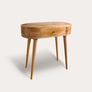 May include: A light brown, oval-shaped wooden side table with a single drawer and four tapered legs. The drawer has a small, dark knob. The table is made of natural wood and has a mid-century modern design.