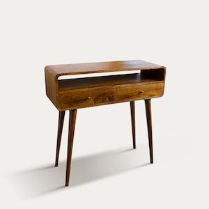 May include: A wooden console table in a mid-century modern style, featuring two drawers and a shelf. The table has a warm brown finish, rounded edges, and tapered legs. The drawers have small, round knobs.
