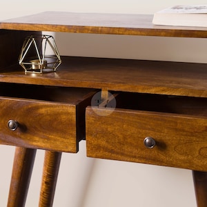 May include: A wooden side table with two drawers and a shelf. The table has a curved top and rounded edges. The drawers have metal knobs. The table is on a light background.