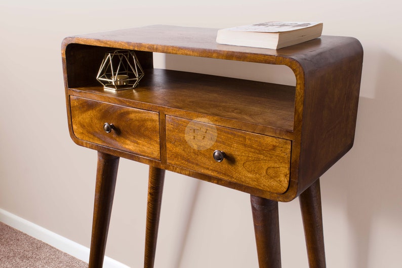 May include: A wooden side table with two drawers and a shelf. The table has a curved top and tapered legs. The table is made of dark wood and has a natural finish.