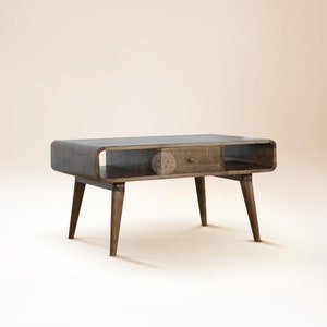 May include: A dark wood coffee table with a curved top and a single drawer. The table has four tapered legs and a shelf underneath the top.