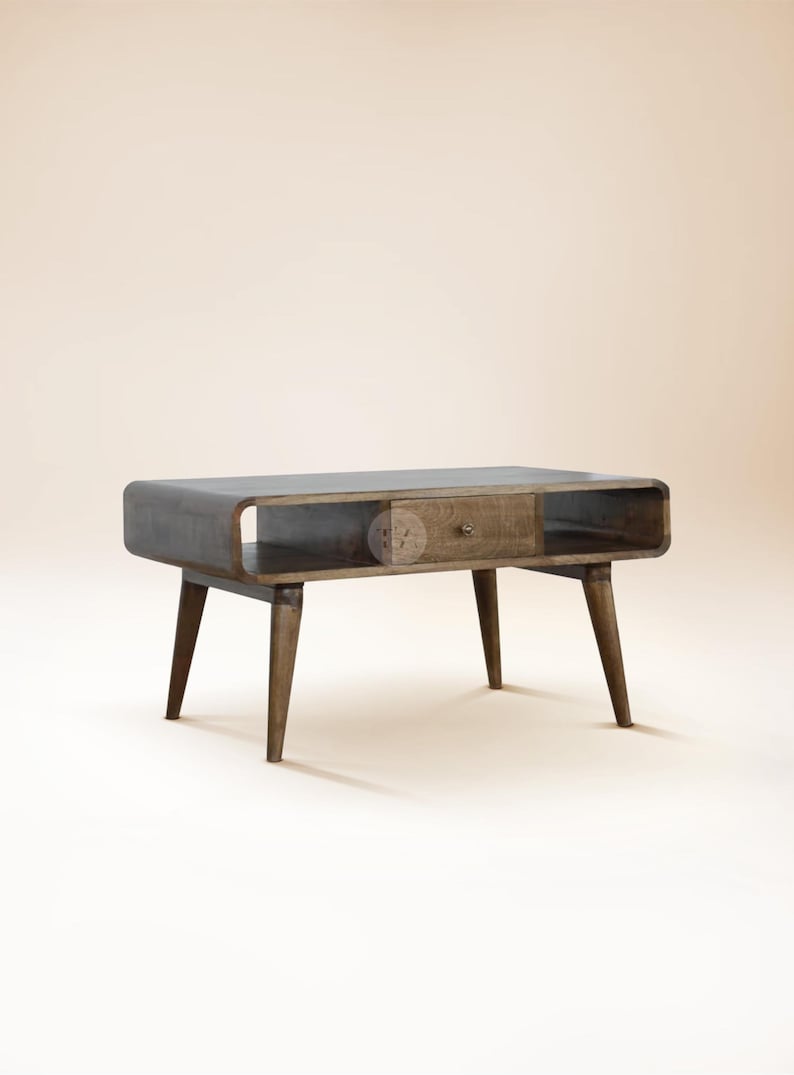 May include: A dark wood coffee table with a curved top and a single drawer. The table has four tapered legs and a shelf underneath the top.