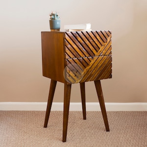 May include: A wooden bedside table with two drawers and a geometric pattern on the front. The table has four legs and is finished in a dark brown colour.