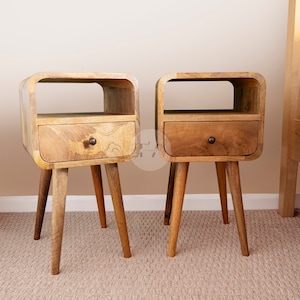 May include: Two wooden bedside tables with a single drawer and a shelf. The tables have a curved design and are supported by four legs.
