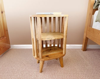 May include: A light brown wooden end table with two shelves and a rounded top. The table has four legs and is made of natural wood.
