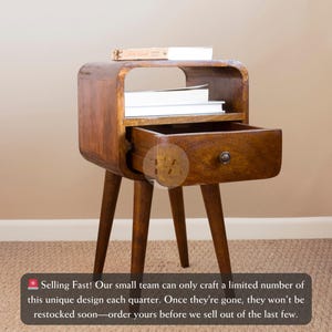 May include: A wooden side table with a curved shelf and a drawer. The table has a dark brown finish and four legs. The drawer is open and the shelf is empty.