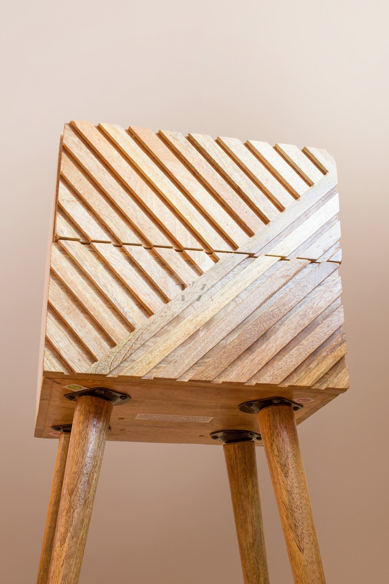 May include: A wooden side table with a geometric pattern on the top and four wooden legs. The table is made of light brown wood and has a natural finish.
