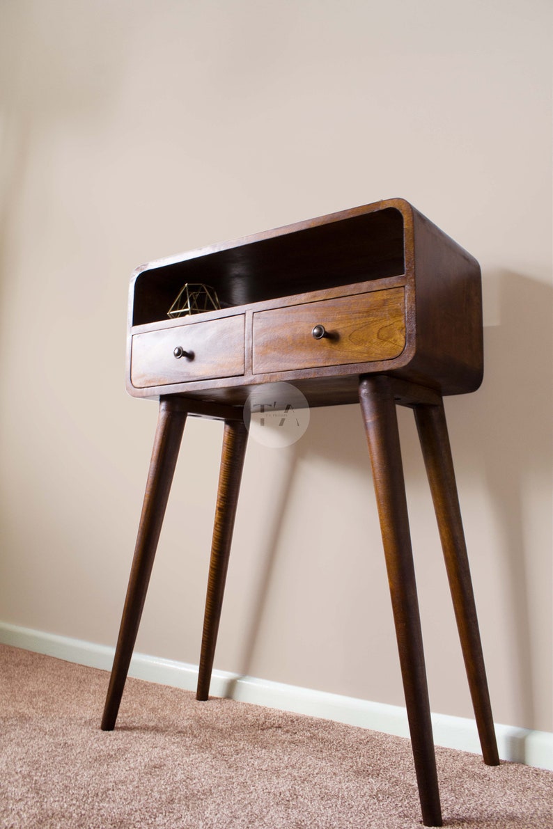 May include: A dark brown wooden console table with two drawers and a shelf. The table has a curved top and four tapered legs.