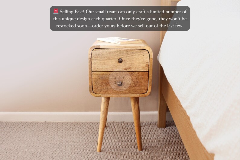 May include: A two-drawer wooden bedside table with rounded edges and tapered legs. The bedside table is made of light brown wood and has a natural finish. The drawers have metal knobs. "Selling Fast! Our small team can only craft a limited number of this unique design each quarter. Once they're gone, they won't be restocked soon-order yours before we sell out of the last few."