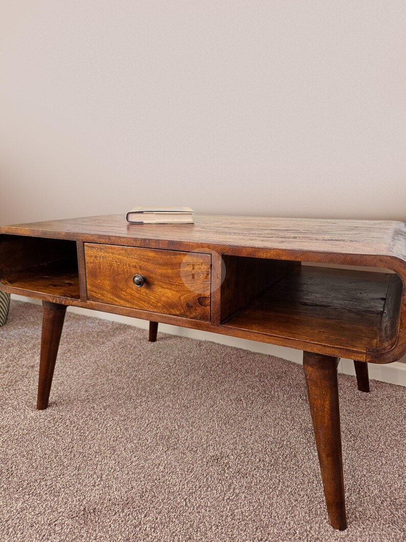 May include: A wooden coffee table with a drawer and open shelves. The table has a dark brown finish and is supported by four tapered legs.