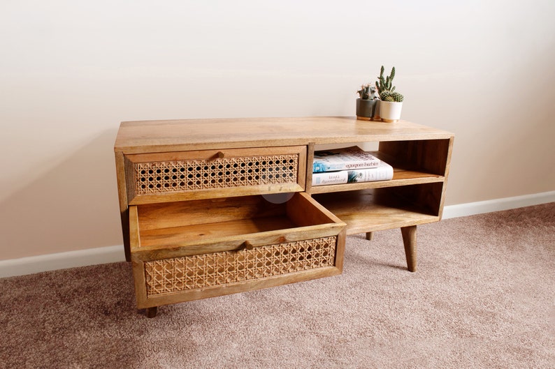 Pu&ograve; includere: Un mobile TV in legno chiaro con due cassetti e due ripiani. I cassetti hanno una parte anteriore in rattan intrecciato. Il mobile ha un design moderno con gambe affusolate.