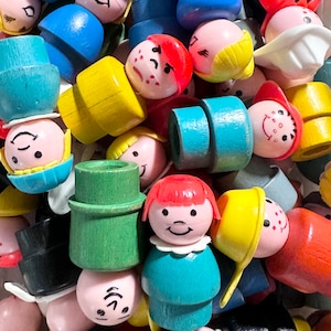 May include: A collection of vintage plastic toy people, some with painted faces and hair, in various colours, including red, blue, yellow, green, and white. The toys are made of plastic and have a variety of shapes and sizes.