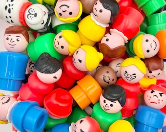 May include: A collection of small plastic toy figures with rounded heads and bodies in various colors including red, blue, yellow, green, and orange. The figures feature simple painted facial expressions and hair styles, with some depicting animals and others people.
