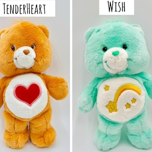 May include: Two plush bear toys. The left bear is orange with a red heart emblem on its white belly and the text Tenderheart above it. The right bear is mint green with a yellow shooting star and rainbow emblem on its white belly and the text Wish above it.