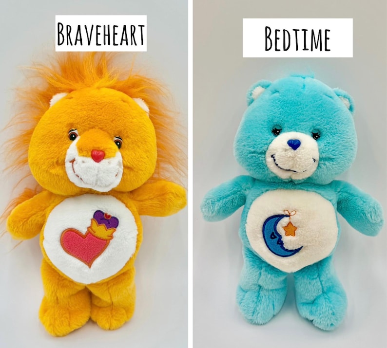 May include: Two plush toys labeled Braveheart and Bedtime. The orange Braveheart lion features a heart and crown emblem on its belly. The blue Bedtime bear features a crescent moon and star emblem on its belly. Both have white muzzles.