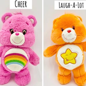 May include: Two plush bear toys. The left bear is bright pink with a rainbow emblem on its white belly and the text Cheer above it. The right bear is orange with a yellow star emblem on its white belly and the text Laugh-A-Lot above it.