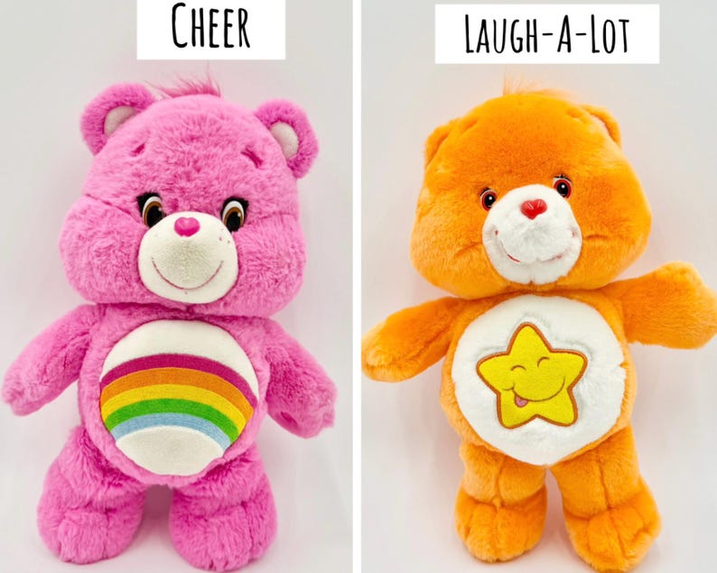 May include: Two plush bear toys. The left bear is bright pink with a rainbow emblem on its white belly and the text Cheer above it. The right bear is orange with a yellow star emblem on its white belly and the text Laugh-A-Lot above it.