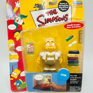 May include: A Playmates World of Springfield interactive figure of Uter, from The Simpsons, in its original packaging. The packaging features the show's logo and character art, and the text "Intelli-Tronic Voice Activation".