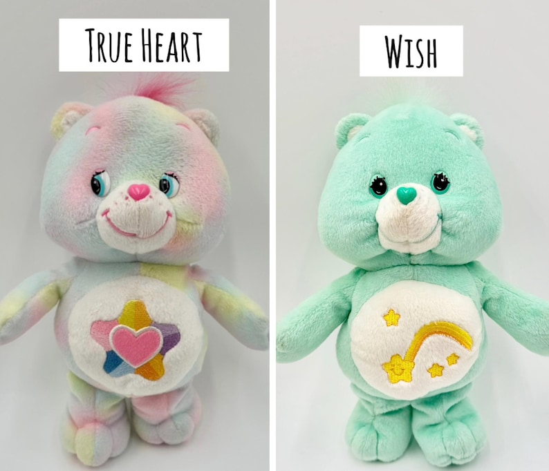 May include: Two plush bear toys. The left bear is multicolored with a pastel tie-dye pattern and a belly badge featuring a pink heart inside a star. The text above reads True Heart. The right bear is mint green with a shooting star belly badge. Text reads Wish.