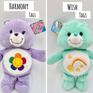May include: Two plush bear toys with tags. The left bear is purple with a textured corduroy-like fabric and a flower belly badge. The right bear is mint green with a smooth fabric and a rainbow and star belly badge. Text reads HARMONY TAGS and WISH TAGS.
