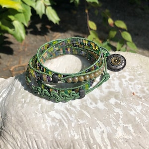 May include: A green, brown, and purple beaded wrap bracelet with a metal button closure.